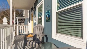 A porch with a white railing, a chair, and a table.