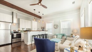 A modern kitchen with white cabinets, a stainless steel refrigerator, and a wooden ceiling.