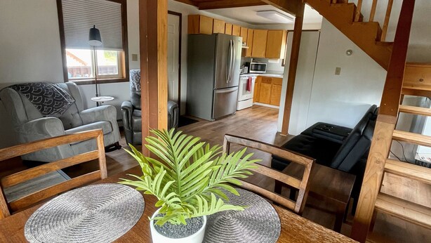 A dining area with a wooden table, chairs, and a potted plant. - Peaceful Acres Cabin 2 - Eagle's Nest  (Soldotna)