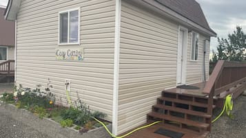 Step up to the Cozy Cottage's inviting front porch, where a hose provides easy access to fresh water.