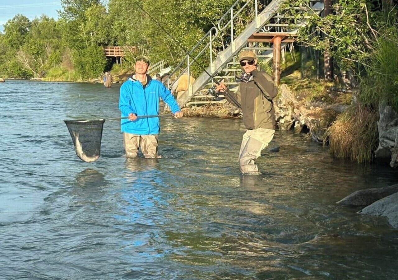Deux personnes pataugeant dans une rivière, tenant des filets de pêche.