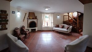 Amplia sala de estar con chimenea, una escalera y vistas al exterior.