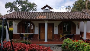 Un edificio con techo de tejas, una entrada central con puertas dobles y un patio cubierto.