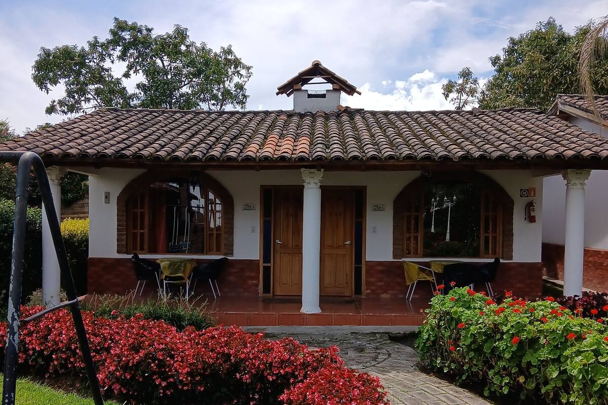 Un edificio con techo de tejas, una entrada central con puertas dobles y un patio cubierto.
