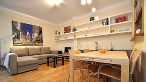 A modern living room with a sofa, dining table, chairs, a coffee table, and a painting on the wall.