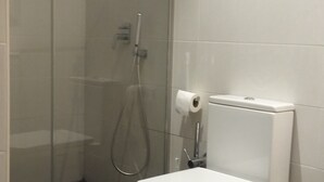 A bathroom with a glass shower enclosure, a toilet, and a towel rack.