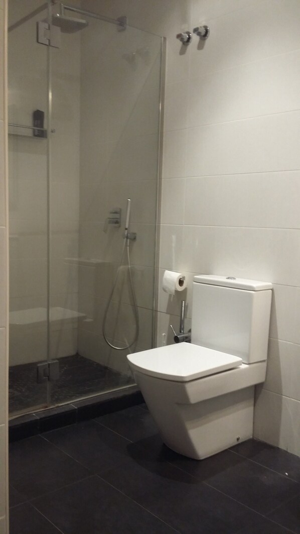 Un baño con cabina de ducha de vidrio, inodoro y perchero para toallas.