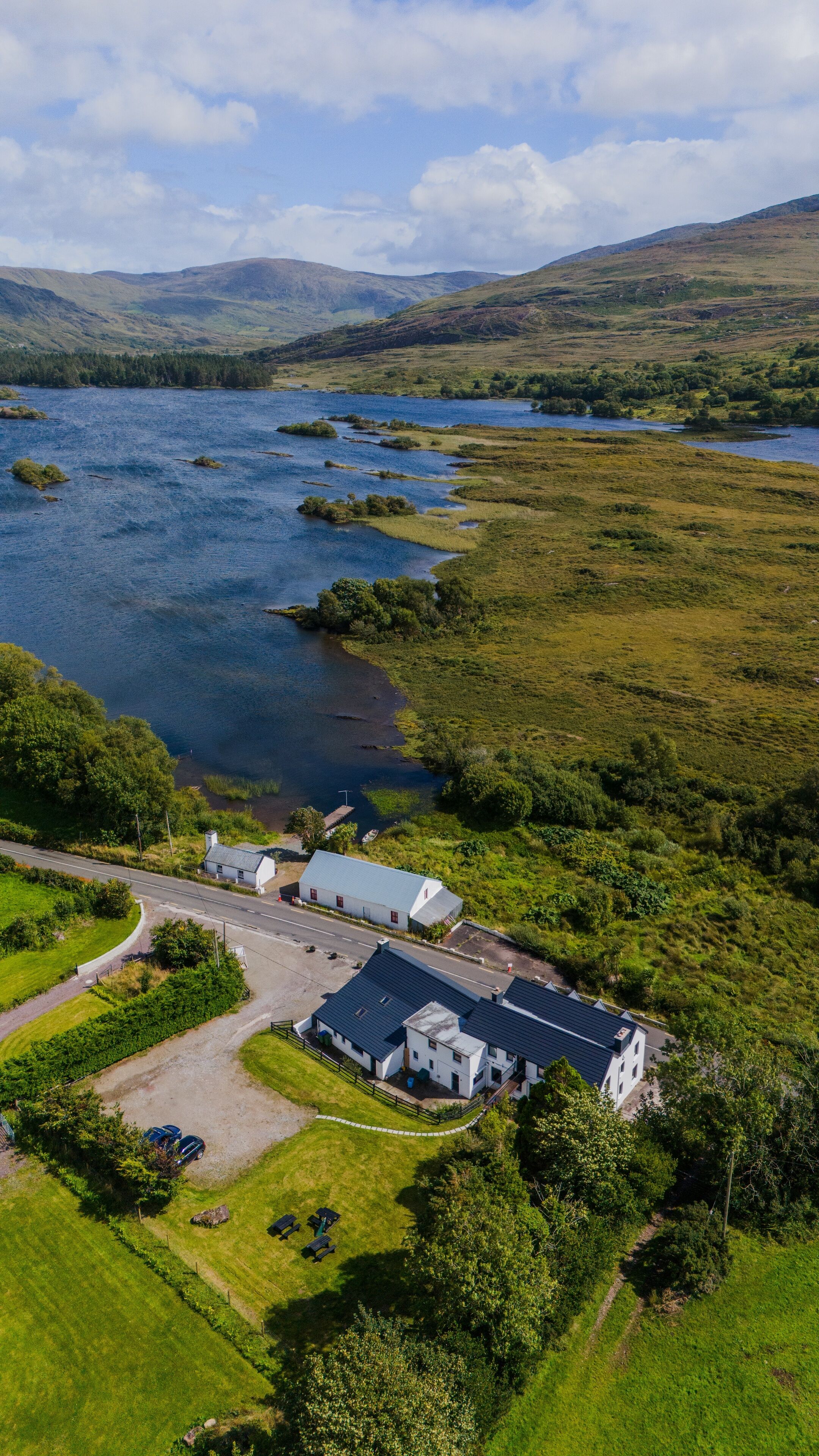 An aerial view of a property with a large building, a lake, and surrounding greenery.