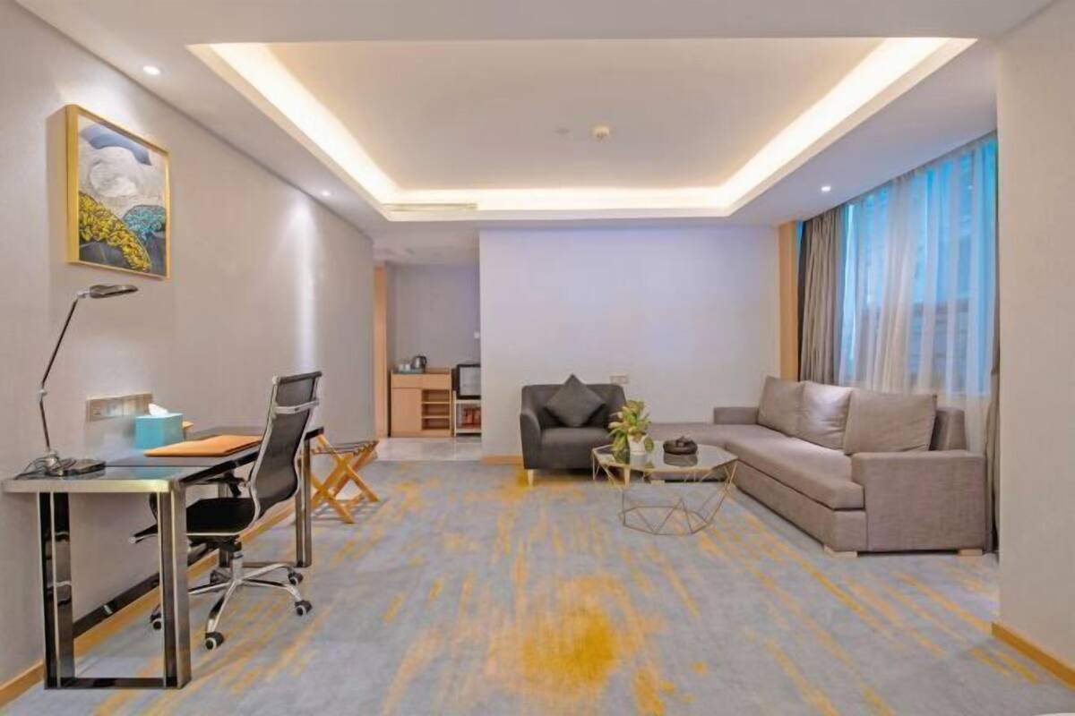 A modern living room with a desk, two sofas, a coffee table, and a painting on the wall.