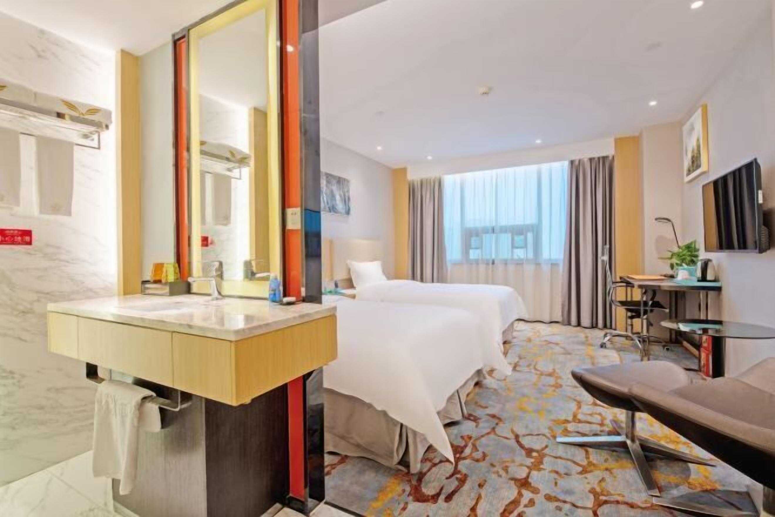 A hotel room with a large mirror, two beds, a desk, a chair, and a view of the outside.