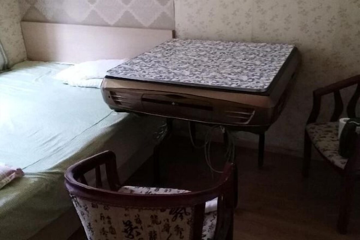 A room with a bed, a table, and two chairs.