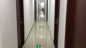 Un pasillo largo y estrecho con piso de baldosas brillantes y una señal de salida verde.