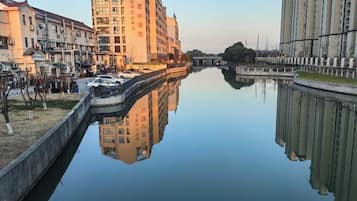 A canal with buildings on either side, a boat docked on the left, and a clear reflection in the water.
