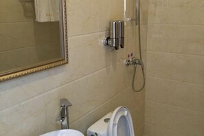 A bathroom with a toilet, a mirror, and a shower. - Xinglan Hotel (Shanghai)