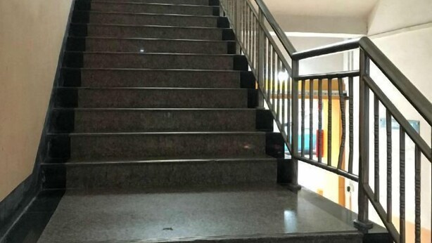 Una escalera con barandales y pasamanos negros que conduce a un piso superior.