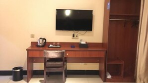 Habitación compacta con un escritorio de madera, una silla, un televisor montado en la pared y un armario.