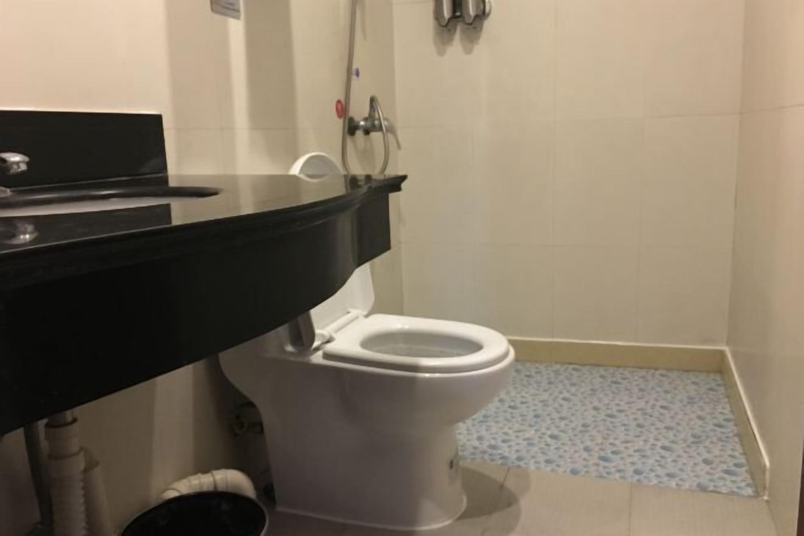 A bathroom with a white toilet, a black sink, and a tiled floor.