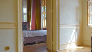 A room with a wooden floor, a bed with a patterned bedspread, and a blue rug. - Anthea Otel (Adalar)