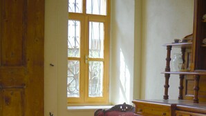 A room with a wooden door, a red armchair, a wooden cabinet, and a patterned rug. - Anthea Otel (Adalar)