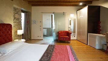 Ein Schlafzimmer mit einem großen Bett, einem roten Sessel, Holzboden und einer Steinwand.