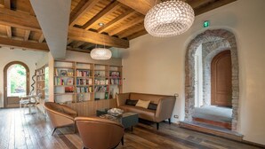 Een knusse bibliotheek met boekenkasten, lederen meubels en een stenen boog.
