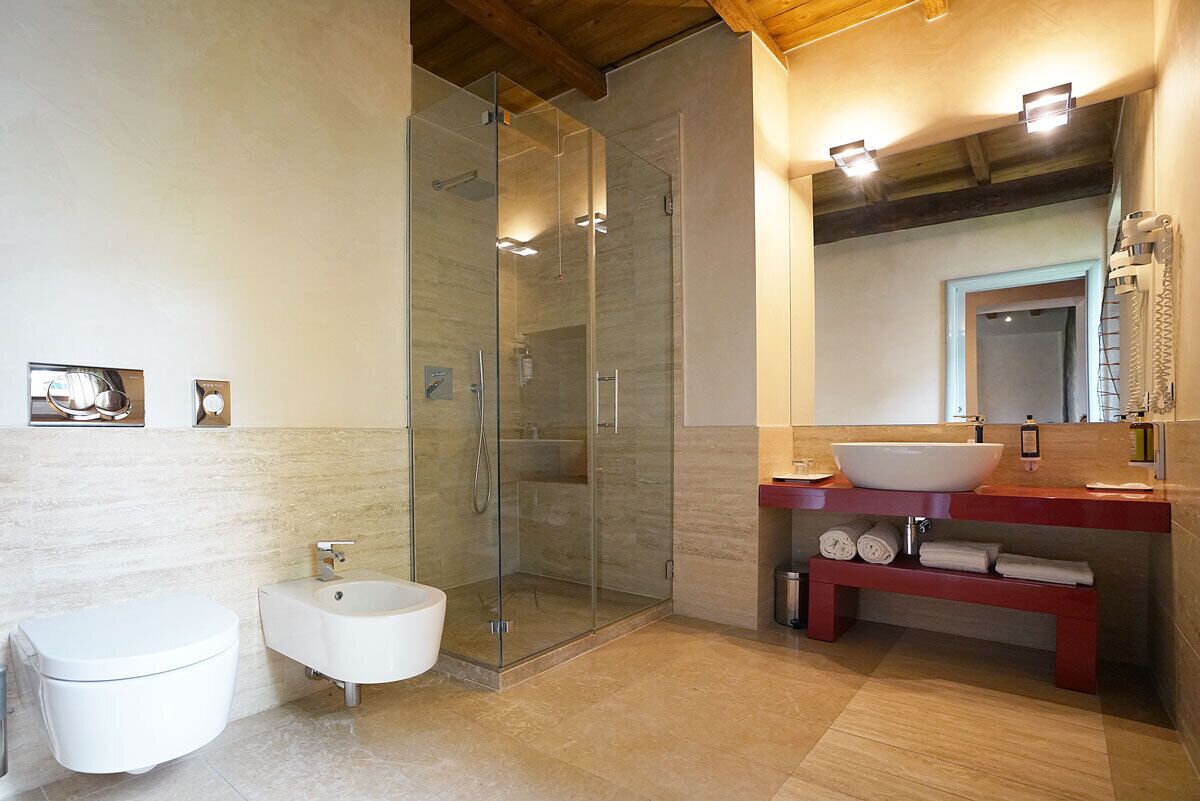 Ein modernes Badezimmer mit einer Duschkabine, einem weißen Bidet und einem Waschtisch mit großem Becken und roter Arbeitsplatte.