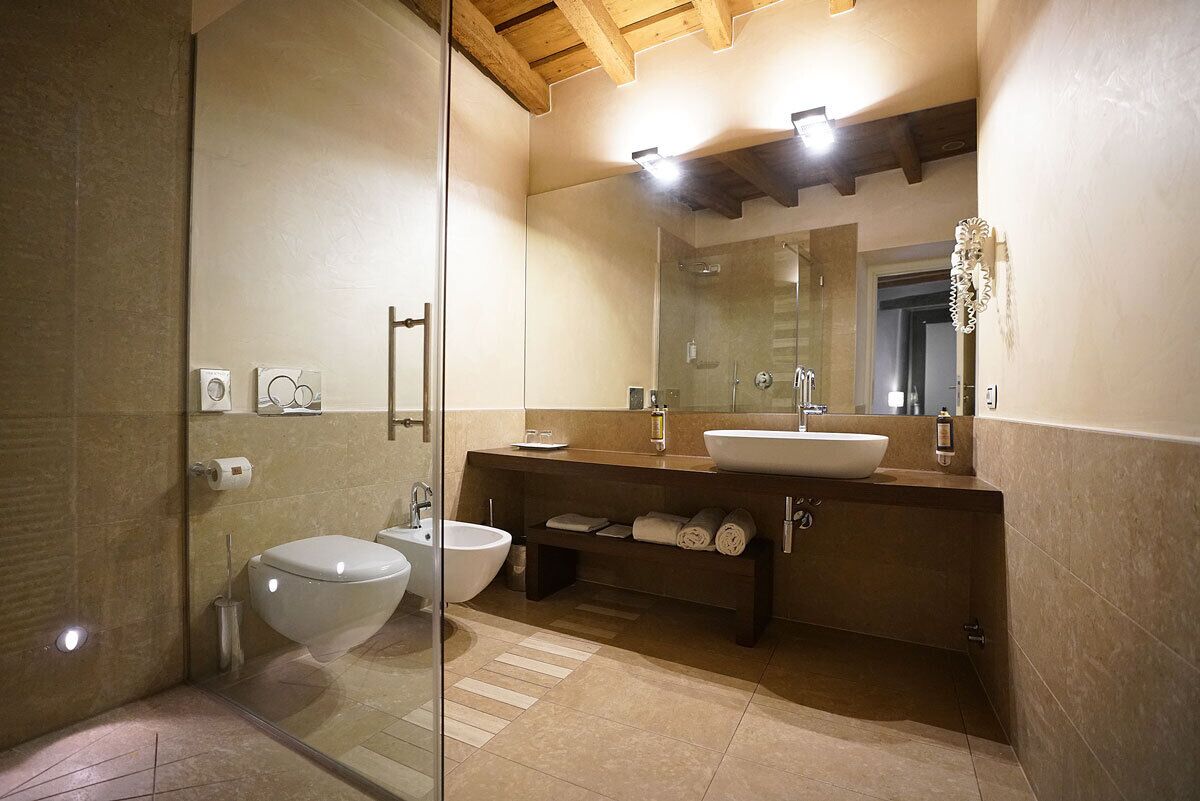 A modern bathroom with a glass shower enclosure, a white toilet, a bidet, a sink, and a vanity with towels.