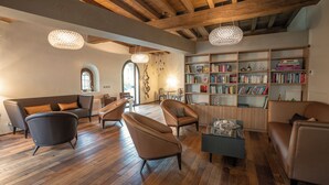 Een ruime woonkamer met houten vloeren, leren banken, een salontafel en een boekenkast vol boeken.