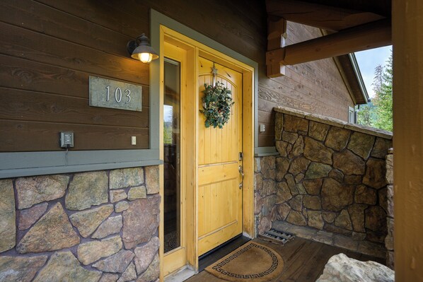 A wooden door with a number '103' above it, a stone wall, and a door mat with a geometric pattern. - Alpine townhouse near Winter Park w/ hot tub (Winter Park)