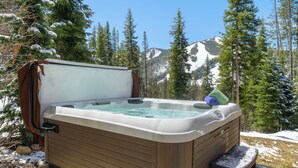 Ein Whirlpool in einer bewaldeten Gegend mit verschneitem Boden und Bergen im Hintergrund.