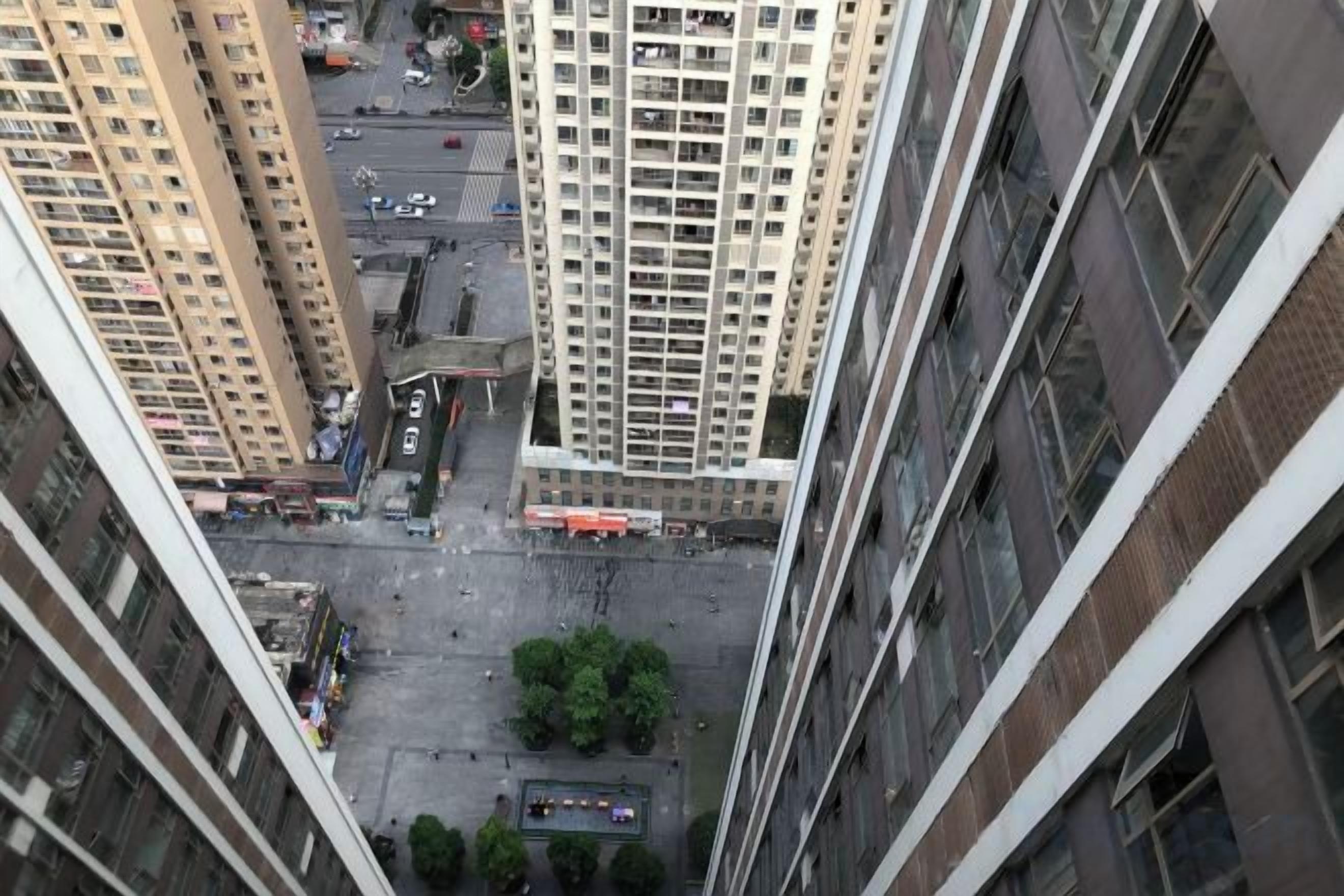 Een hoog gebouw met meerdere verdiepingen, een centrale binnenplaats en omliggende straten.