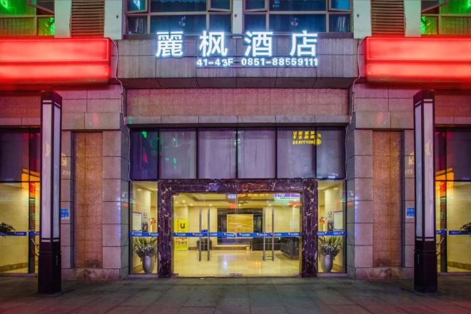 Entrada d'hotel amb un rètol sobre la porta, una recepció i una façana de vidre.