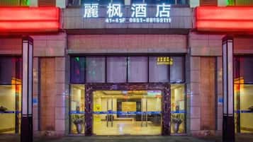 A hotel entrance with a sign above the door, a reception desk, and a glass facade.