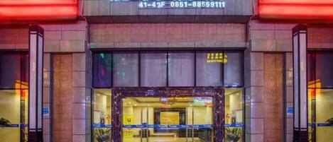 Entrada d'hotel amb un rètol sobre la porta, una recepció i una façana de vidre.