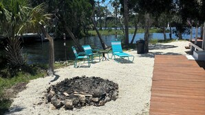 A deck with outdoor seating, a fire pit, and a view of a lake. - Hellgate Island scallop house, boat access only (Homosassa)