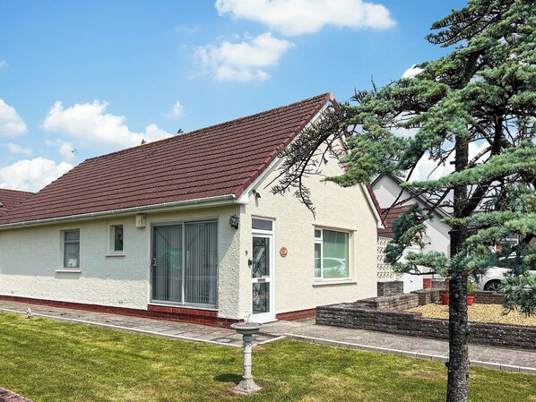 Ein einstöckiges Haus mit rotem Ziegeldach, einem großen Fenster und einer kleinen Veranda.