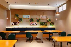 A cafe with wooden tables and chairs, a counter with a menu, and hanging pendant lights. - Homeinn Selected Hotel (Beijing Deshengmen Outer Street) (Beijing)