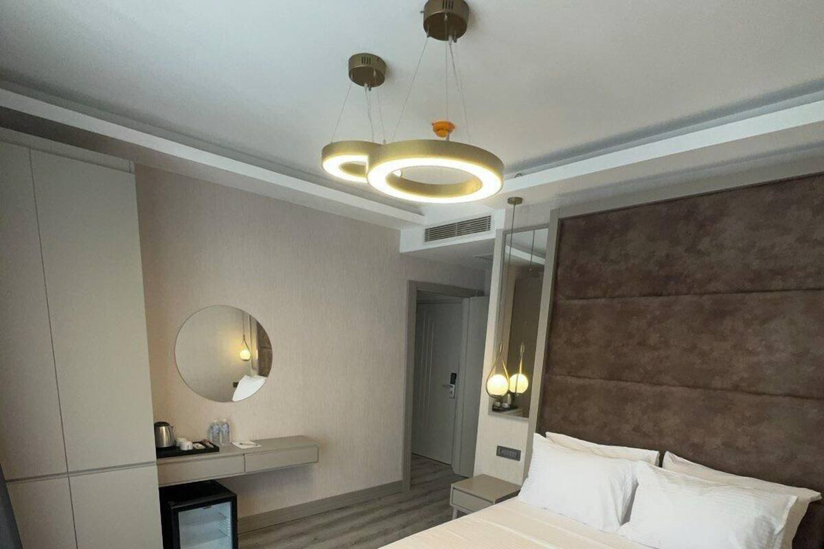 Un dormitorio moderno con una cama grande, un armario empotrado, un espejo redondo y una mesita de noche pequeña.