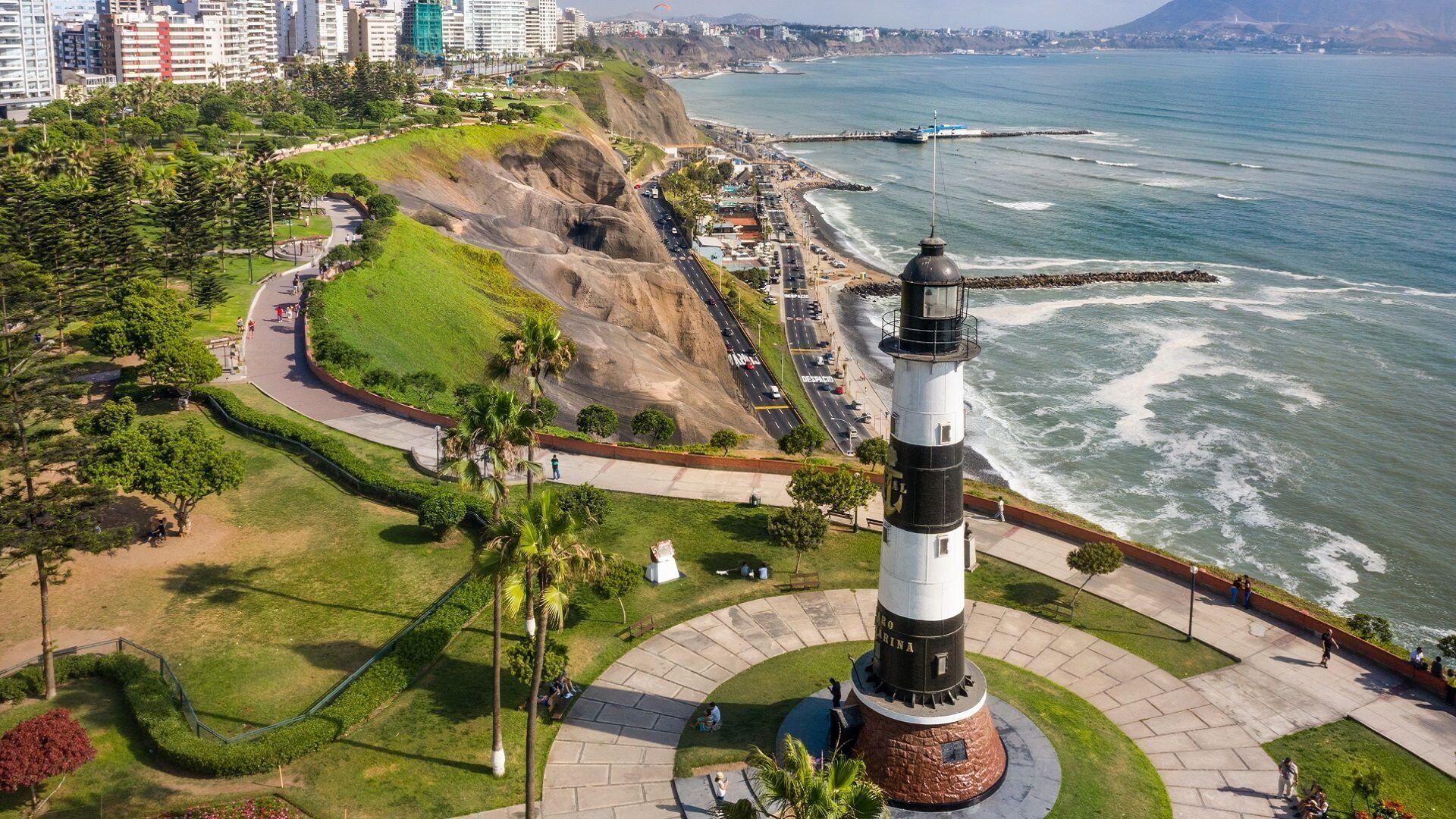 A lighthouse with a circular base, surrounded by a landscaped area with pathways and benches.