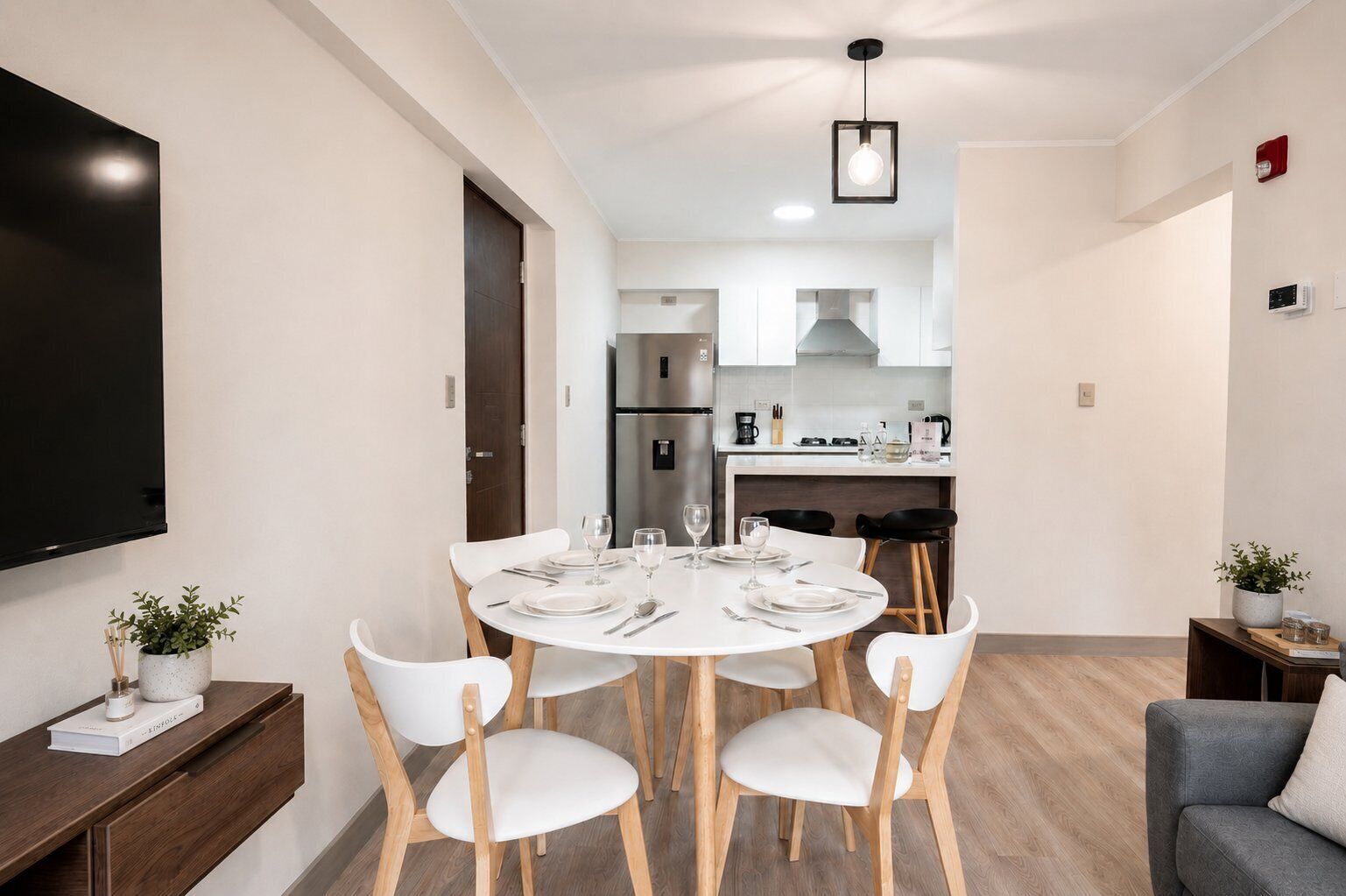 Una sala de estar moderna con comedor, un televisor de pantalla plana y una cocina al fondo.