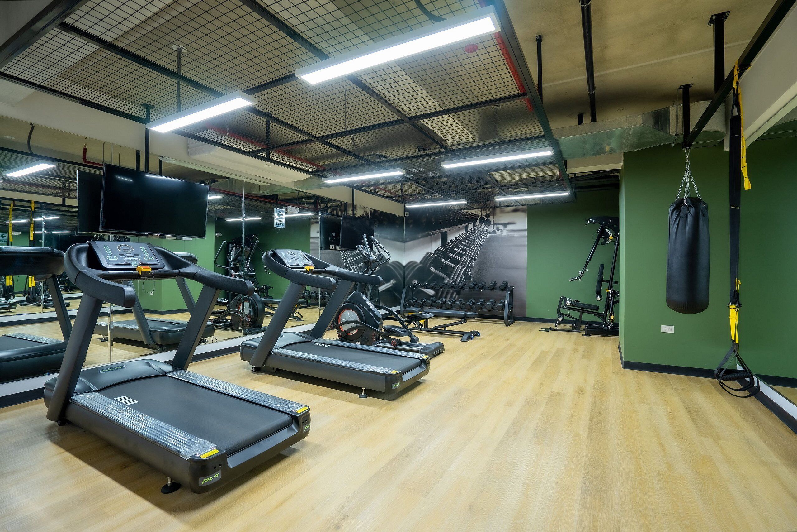 Una palestra con tapis roulant, pesi e un sacco da boxe.