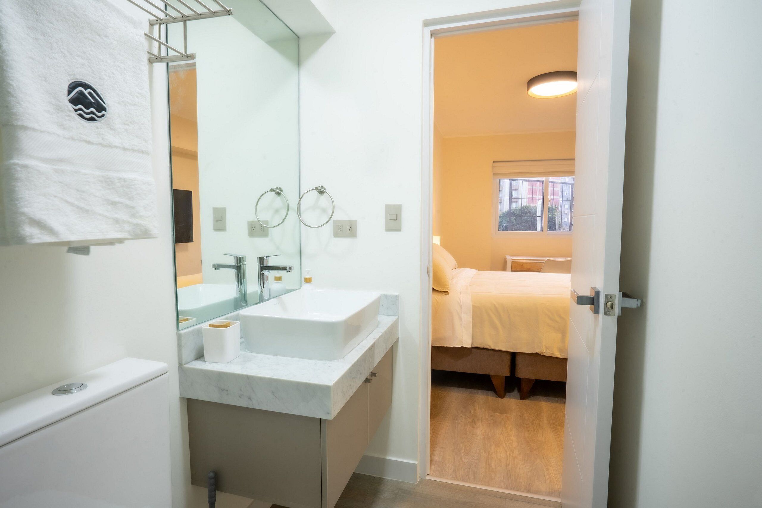 A bathroom with a white sink, mirror, and towel rack.
