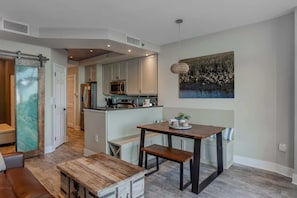 Een moderne keuken met ingebouwde apparatuur, een eethoek met een bank en een groot raam.