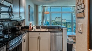 Una cocina moderna con un amplio ventanal, electrodomésticos de acero inoxidable y vista al mar.