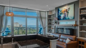 Una cocina moderna con un ventanal grande, una zona de comedor con sofá de cuero marrón y un salón con un cuadro grande.