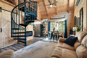 L’intérieur d’un chalet en bois comprend un escalier en colimaçon, un coin repas et un salon confortable.