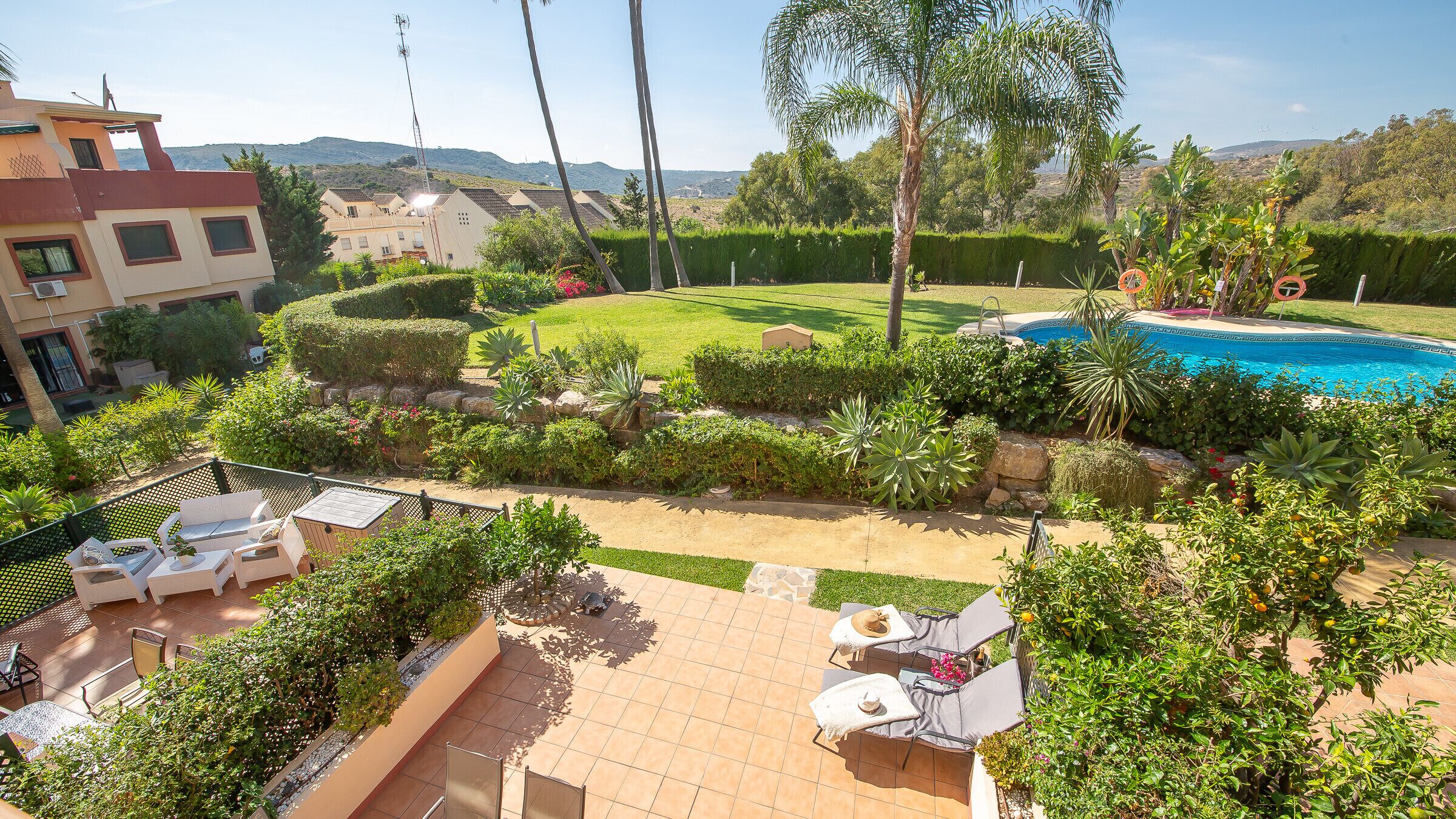 A residential area with a swimming pool, patio furniture, and a well-maintained garden.