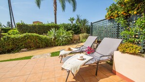 An outdoor patio with two lounge chairs, a small table, and a decorative fence. - Gunilla townhouse no 6 (Manilva)