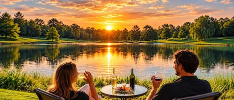 Two people seated at a round table with a view of a lake and sunset.