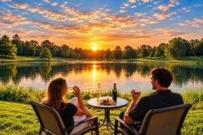 Two people seated at a round table with a view of a lake and sunset. - The Cottage Inn At Amos Lake (Preston)